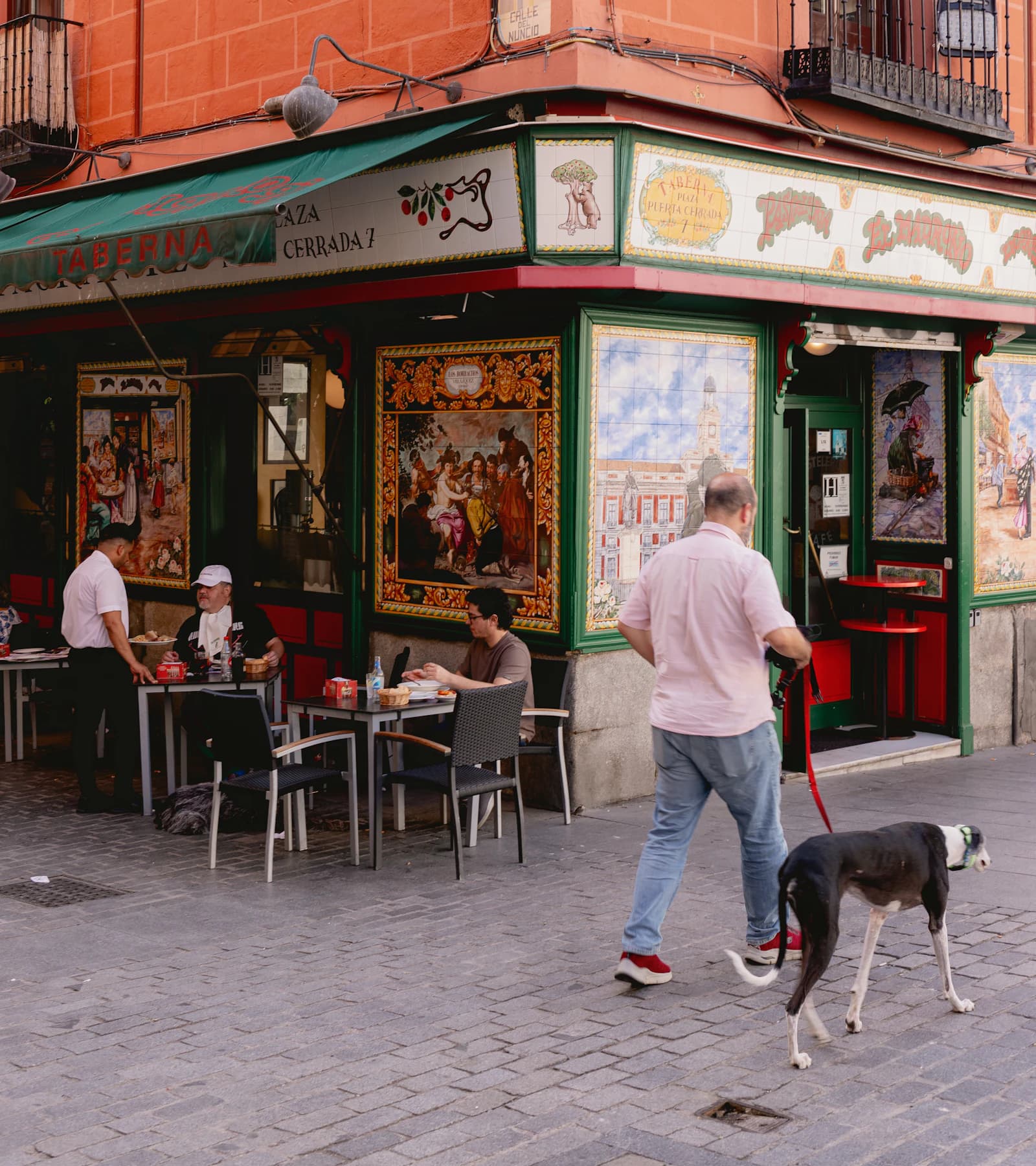 Una persona paseando a su perro frente a un restaurante tradicional de Madrid